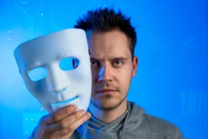 Homem segurando uma máscara de teatro representando uma ameaça de golpes com deepfakes e vozes falsas na era da inteligência artificial.